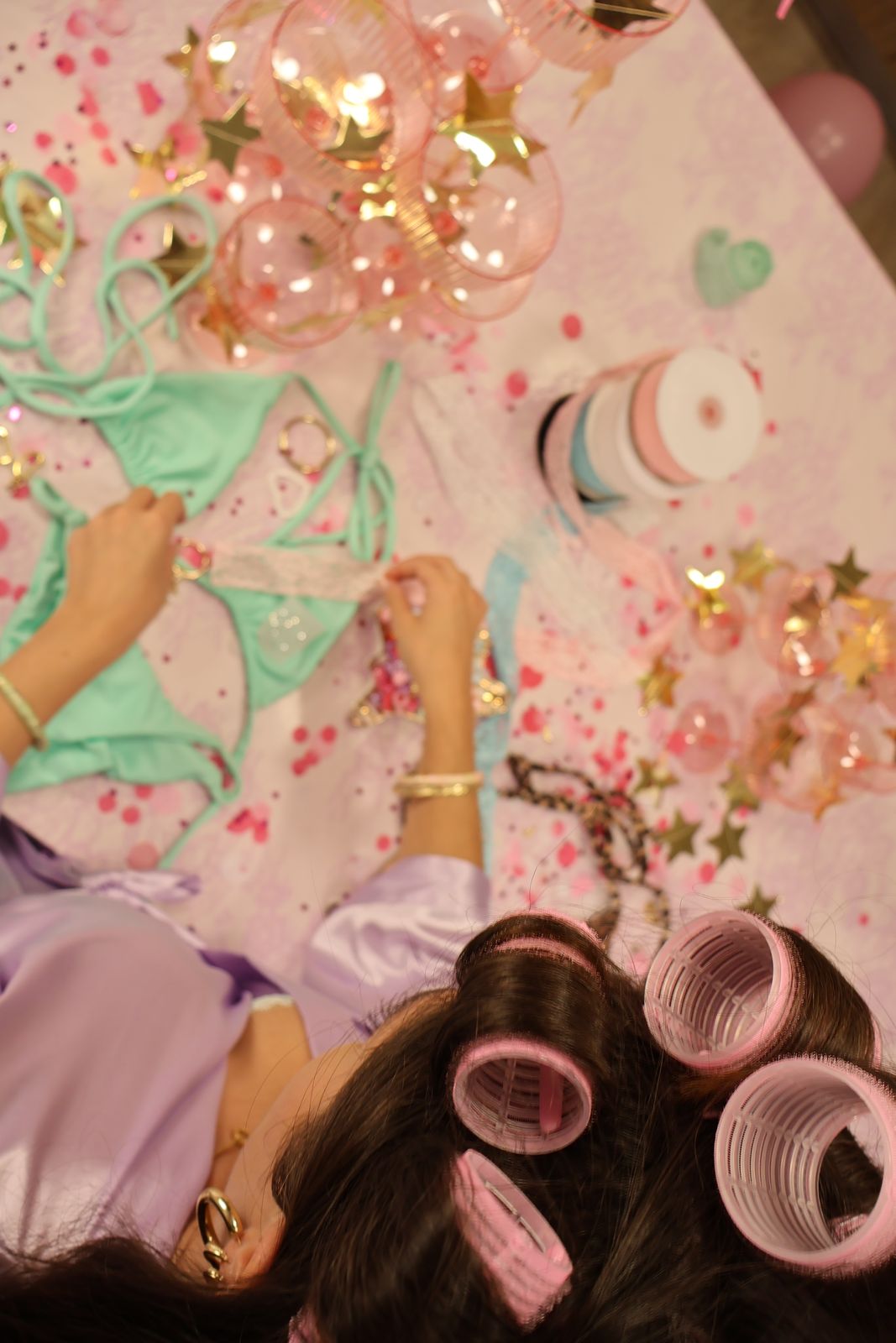 Hands arranging mint bikini ties among rhinestones and confetti